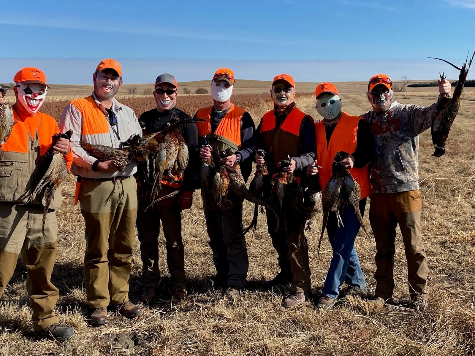 men with masks holding pheasants