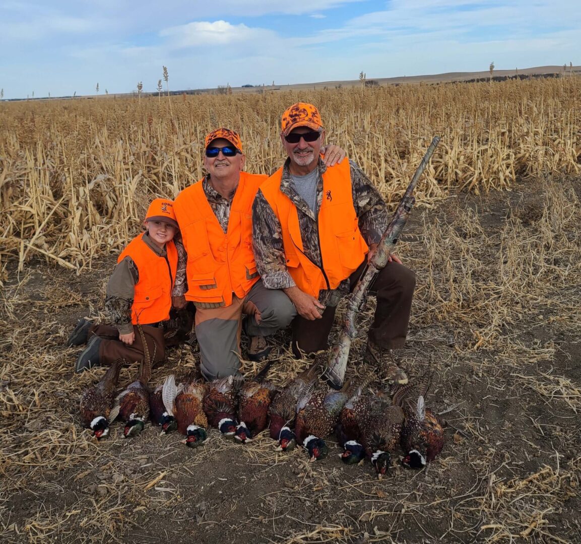 two men and one child posing in front of their hunted pheasants