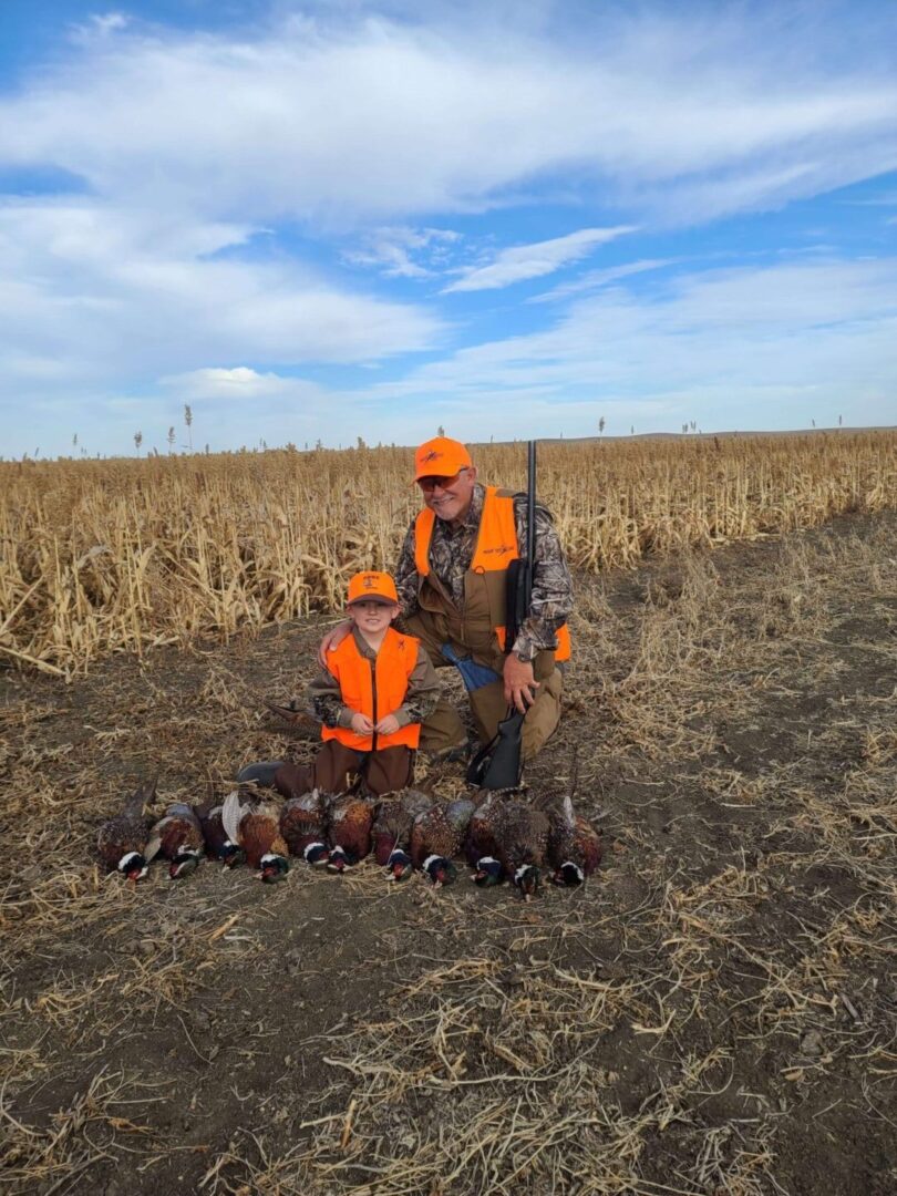 a man and a child posing in front of their hunted pheasants