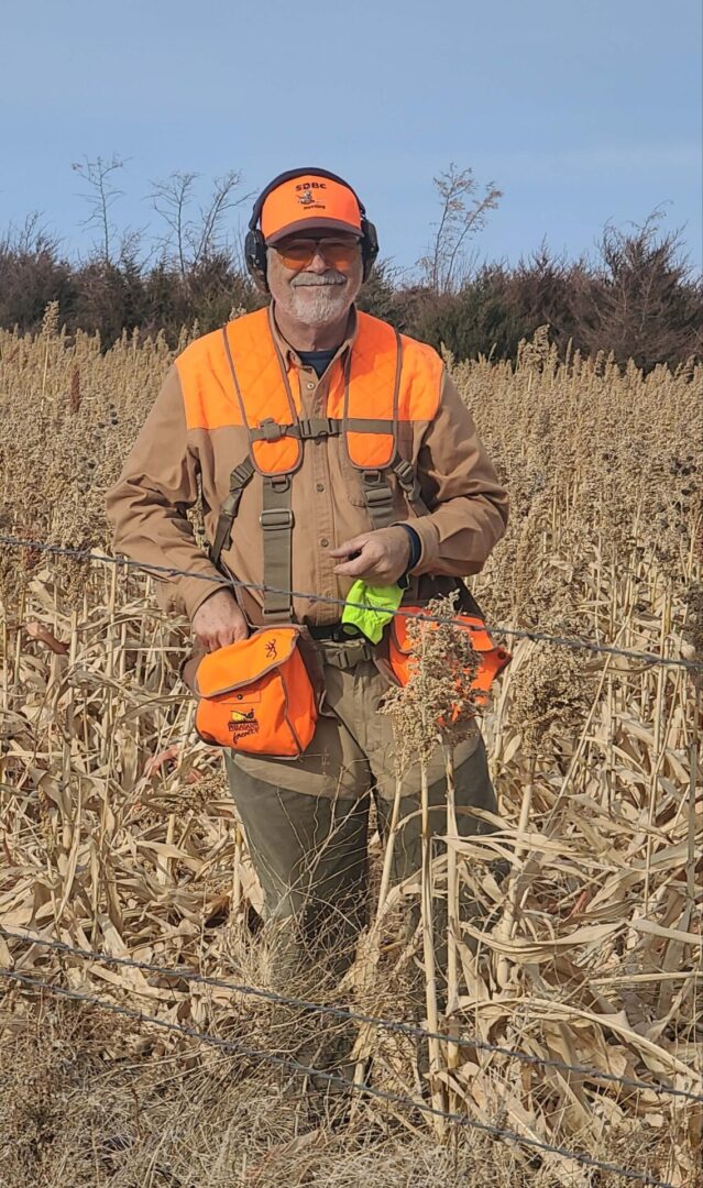 a man with an orange hat and sunglasses standing in a field