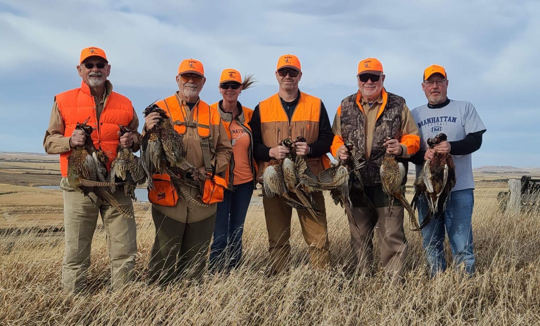 a group of men standing in a row holding hunted pheasants