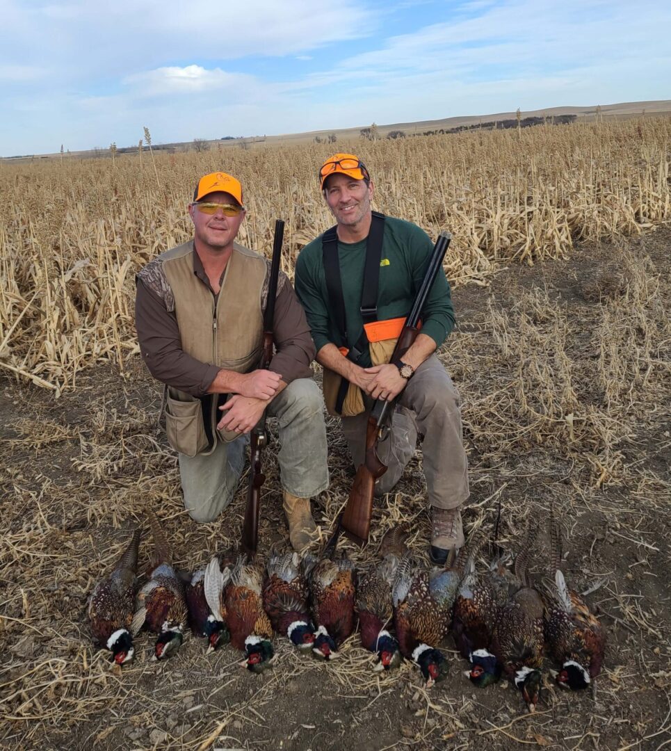 two men with a row of hunted pheasants