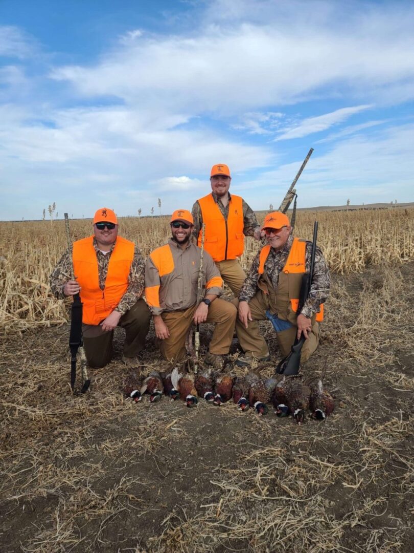 a group of men in a field with their hunted pheasants