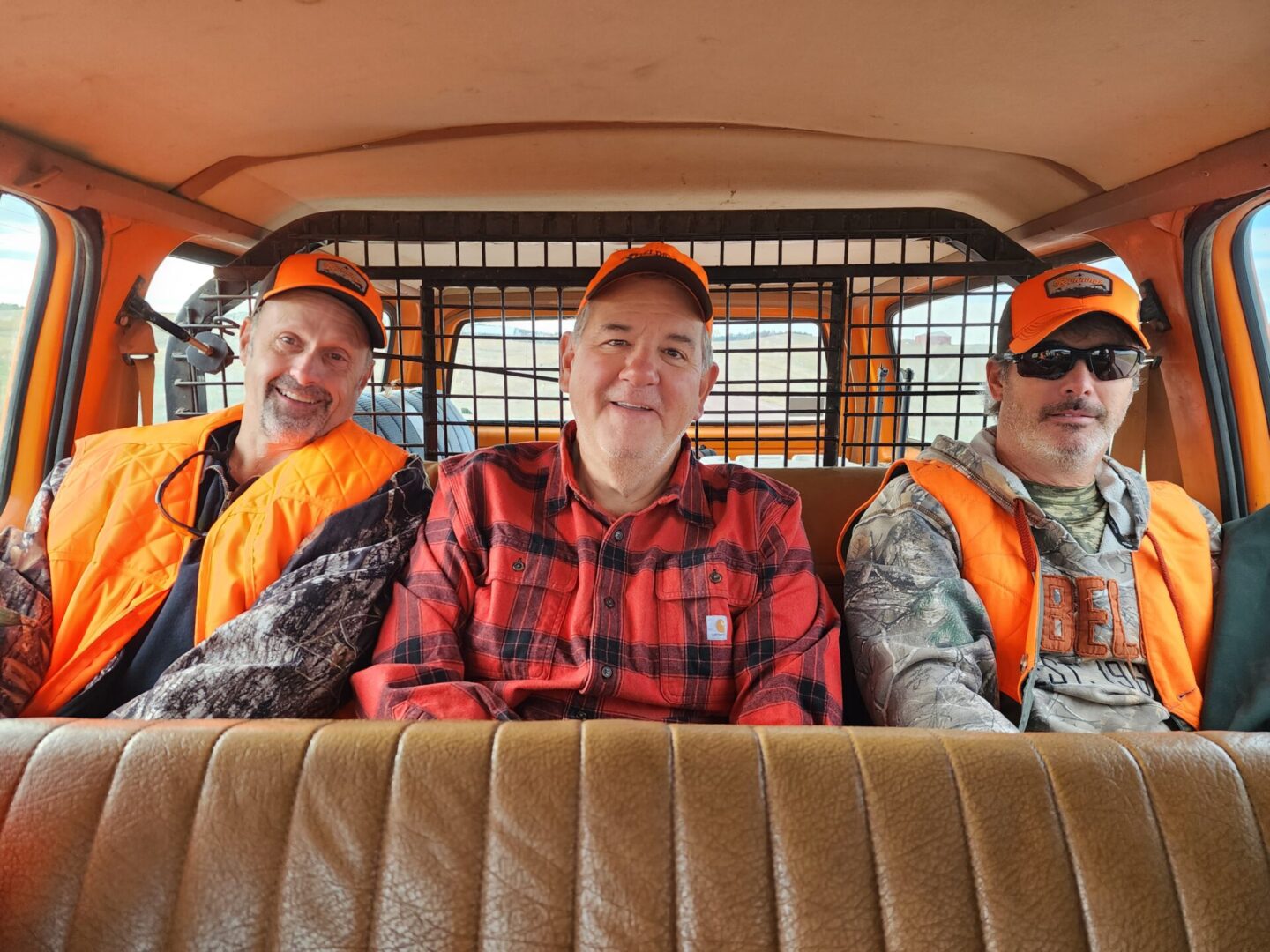 Three People Sitting on Hunting Truck