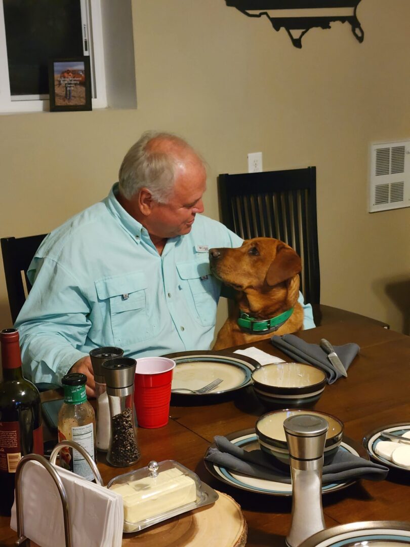 Person Sitting at Dining Place With Dog