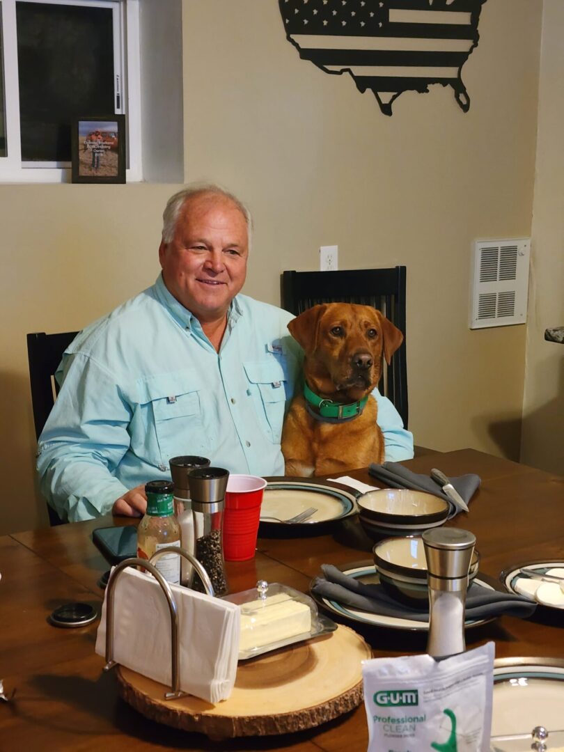 Person Sitting at Dining Table With Dog