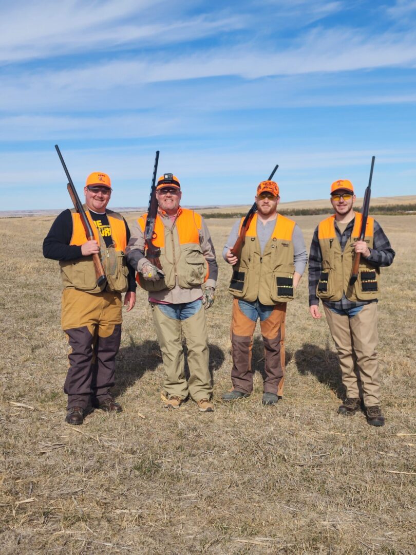 Four Hunters Holding a Gun at Field