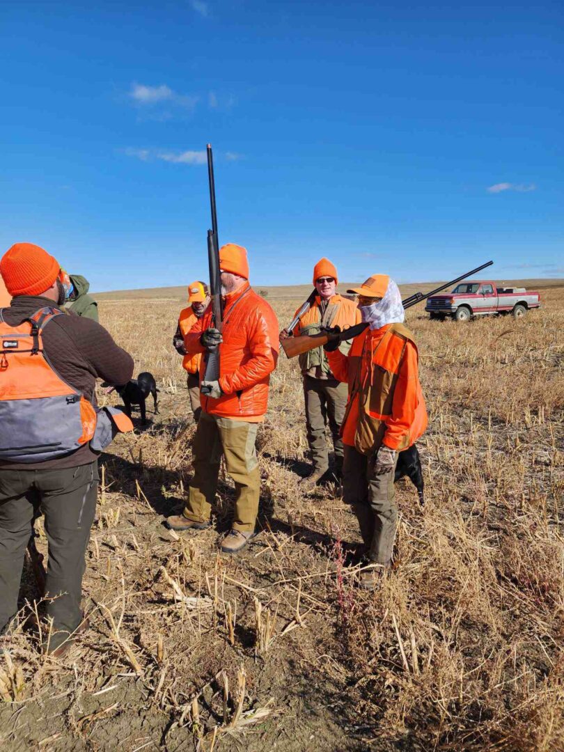 people wearing orange jackets with guns